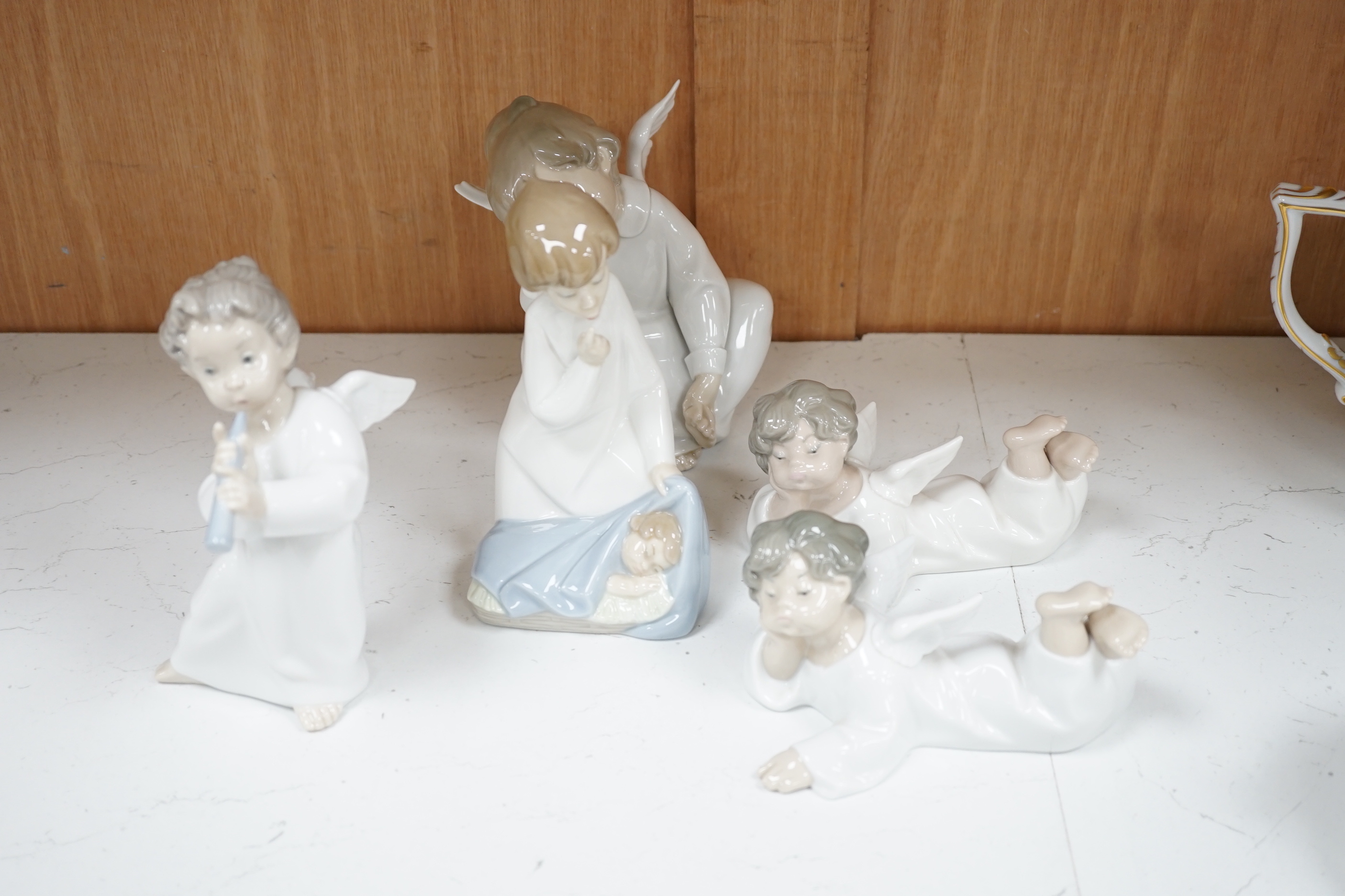 A large Lladro figure of children in a pram, seven models of angels and a boy with a dog (9)